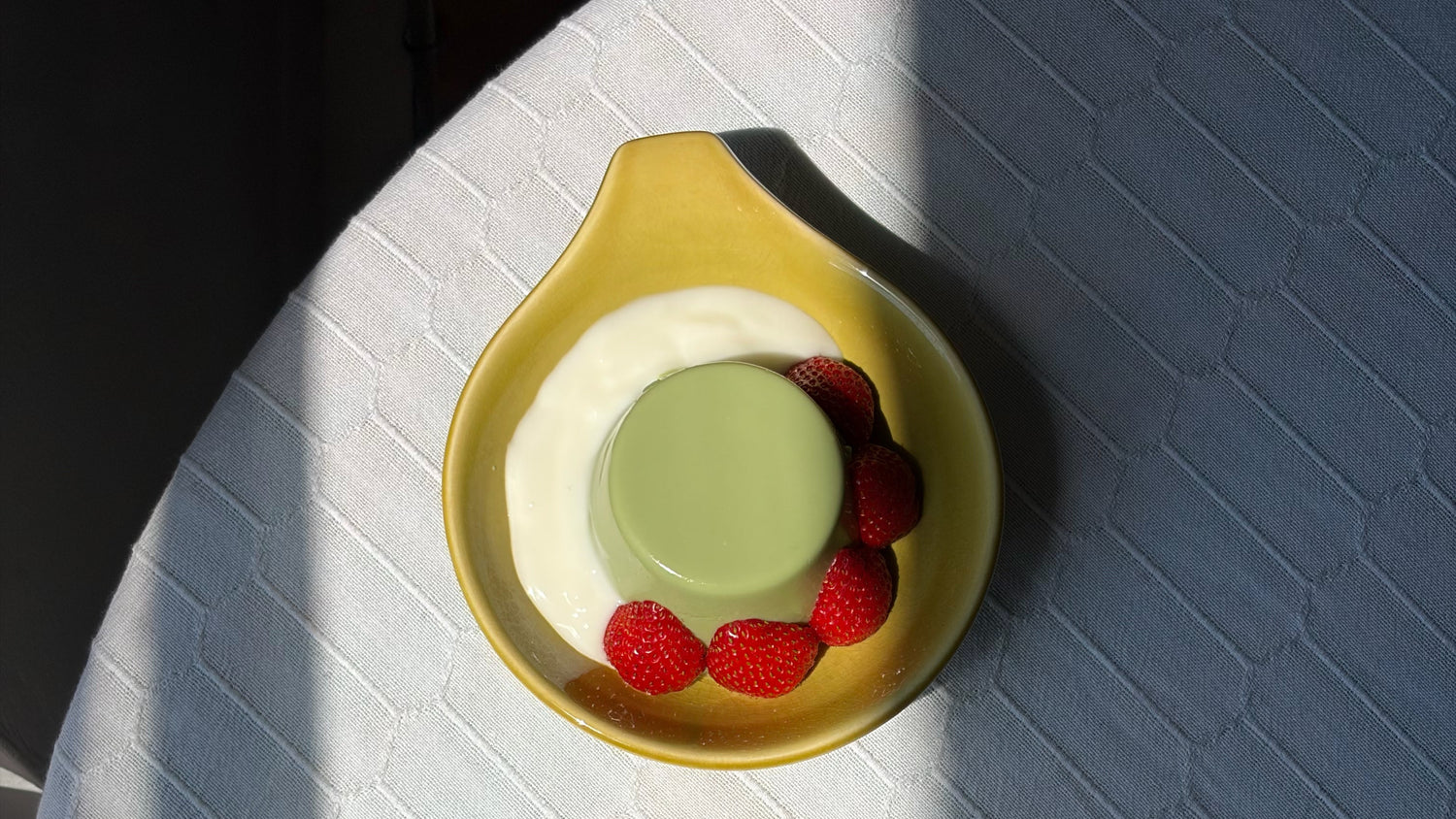 Two small dessert plates with green and red desserts on a textured surface.